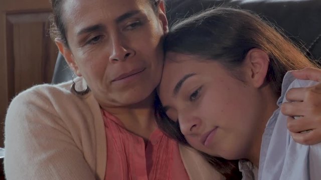 Mexican mother comforting her mixed race teenager child - close up