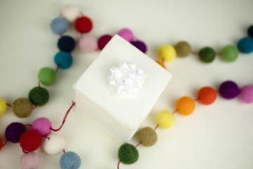 Obraz na płótnie Canvas White gift wrapped box with colorful garland.