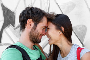 Interracial couple young happy Asian woman and Caucasian man lovers smiling laughing kissing...
