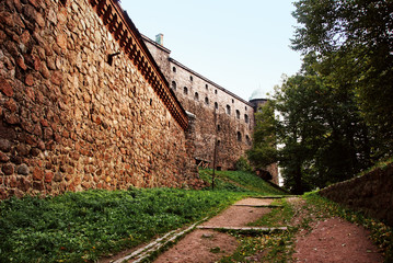 View of the wall and tower of the castle in summer. Path the stone wall. © asyashu