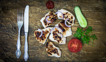 On a wooden tray grilled chicken with vegetables