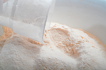 Flour in white Cup with a measuring Cup.