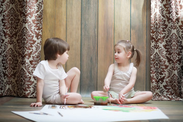 Little children paint on a large sheet of paper