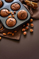 Homemade chocolate muffins (brownies) with cinnamon, almonds and hazelnuts on brown paper background