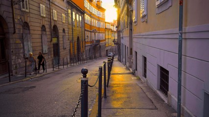 Fototapeta na wymiar Sunset on the narrow street of the old European city. Trieste, Italy