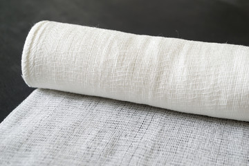 A roll of white medical bandage on a black background.