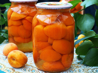 Canned apricots in sweet syrup in two cans on the table, Stocks for the winter, horizontal orientation, closeup