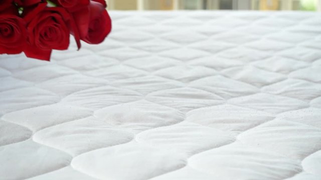 one person put bouquet of red rose flower on the bed