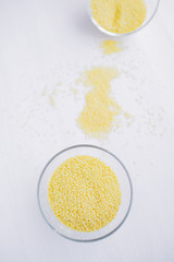 Yellow couscous in a beautiful bowl on a light wooden background