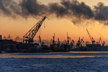Fototapeta na wymiar Harbor cranes on Neva river at sunset in winter. Saint Petersburg. Russia