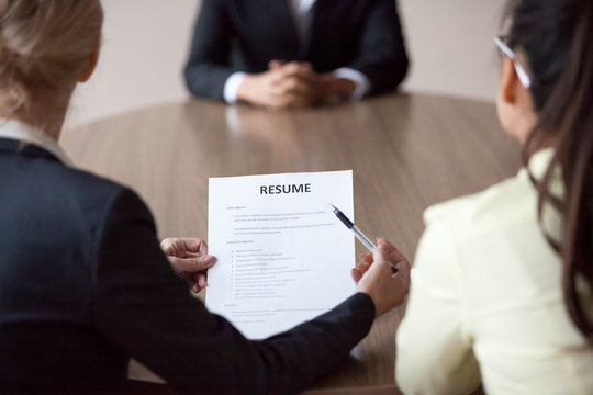 Businesswomen, Director and colleague HR manager interviewing male student candidate in office. Female boss holding cv, close up. Human resources, recruitment concept