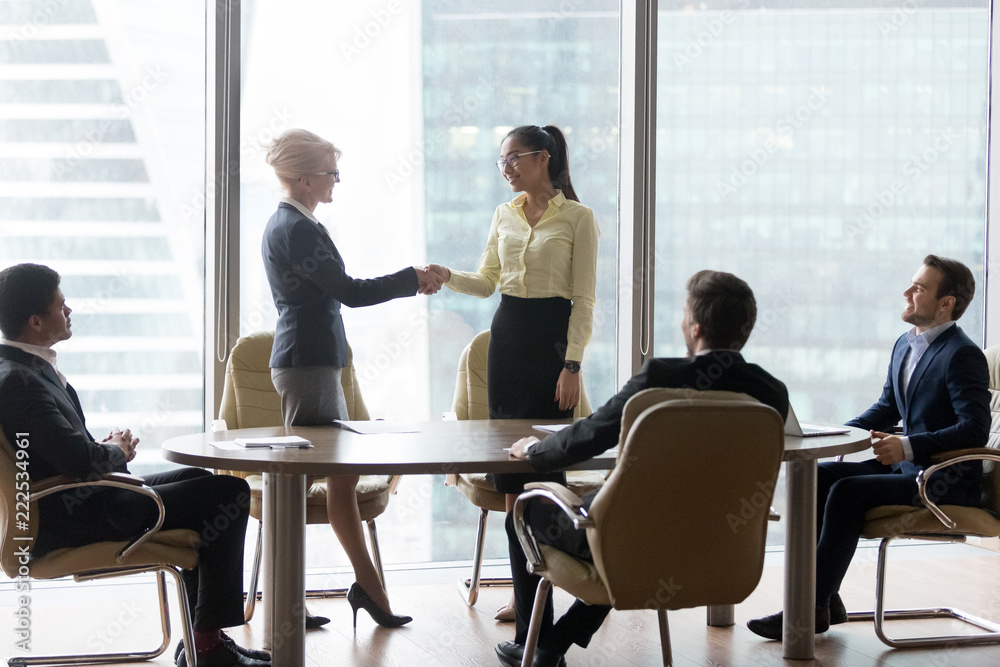 Sticker Smiling multiracial business people at meeting. Mature woman ceo welcomes new colleague greeting, reward or promotion. HR, Client and executor shaking hands. Encourage, retirement and respect concept