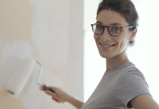 Smiling woman painting walls with a paint roller