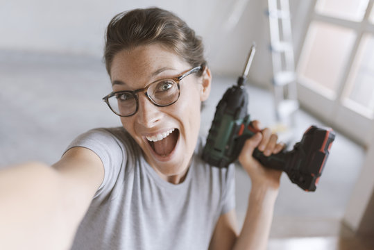 Cheerful woman holding a drill and taking a selfie