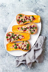 Stuffed butternut squash with chickpeas, cranberries, quinoa cooked in nutmeg, cloves, cinnamon. Thanksgiving dinner recipe. Vegan healthy seasonal fall or autumn food