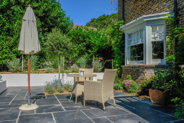 Table and chairs on the patio in an English country garden - obrazy, fototapety, plakaty