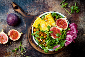 Vegan, detox Buddha bowl recipe with turmeric roasted tofu, figs, chickpeas and greens. Top view, flat lay