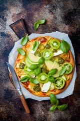 Green pizza with pesto, zucchini, tomatoes, avocado, jalapeno, mozzarella cheese and fresh basil