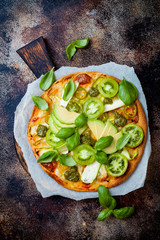 Green pizza with pesto, zucchini, tomatoes, avocado, jalapeno, mozzarella cheese and fresh basil
