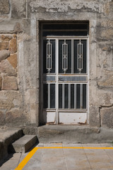 Fototapeta na wymiar Puerta metalica con vidriera en pared de piedra. Galicia. España.