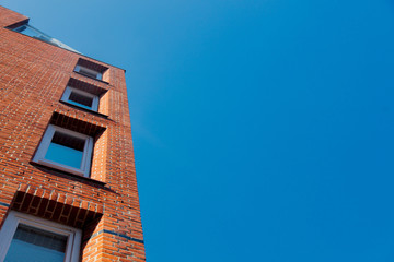 Fototapeta na wymiar View at side of red brick building with modern windows on blue sky background. Bremen, Germnay