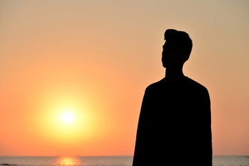 sagome di persone in controluce sulla spiaggia al sorgere del sole