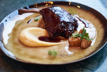 Duck confit with Quinoa puree, celery, apple with cinnamon sauce served on plate. Exclusive restaurant meals