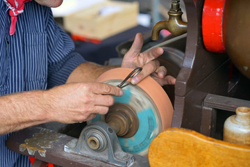 Close-up shot of a man's hands sharpening a scissors. Elderly specialist sharpening a scissors....