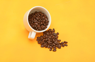 Coffee Beans with tea cup, natural seeds on yellow background