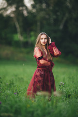 A beautiful young woman in a bard dress is gazing on in the field and the garden.