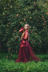 A beautiful young woman in a bard dress is gazing on in the field and the garden.