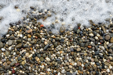 Close-up view of wet pebble in foam bubbles as background.