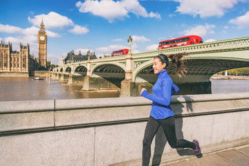 London runner woman running near Big Ben. Europe city Asian girl jogging training at Westminster bridge with red double decker bus. Fitness athlete happy in London, England, United Kingdom.
