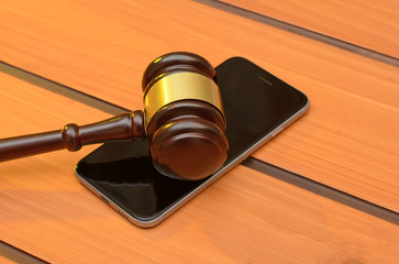 Judge gavel on smartphone, wooden law background
