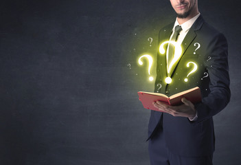 Businessman holding a book with question mark symbol.