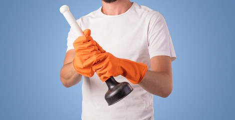 Housekeeper with cleaning product and equipment in front of a blue empty wall
