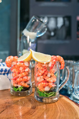 Fresh shrimps with lemon in a beer glass on a wooden tray