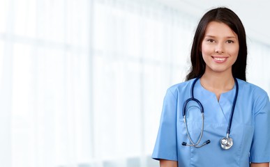 Attractive young female doctor with blurred hospital