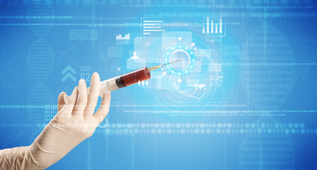 Female doctor hand holding syringe with blue background and charts