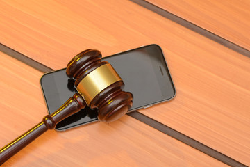 Judge gavel on smartphone, wooden law background