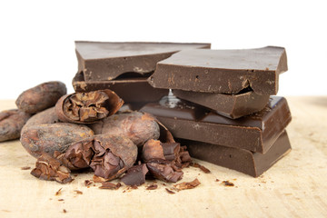 Tasty dark chocolate and cocoa beans on a white table. Sweets used to prepare desserts in the kitchen.