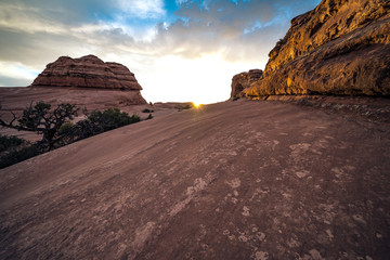 Sunrise on the Delicate Arch trail during the golden hour. Sunburst over the sandstone rock