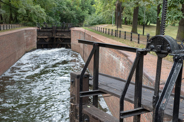 Old sluice on the channel in Central Europe. A wooden dam on the river.