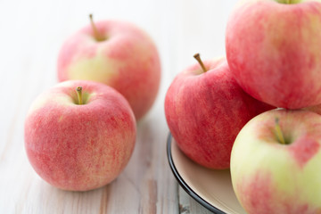 Freshly picked organic light pink apples. White wooden table, high resolution.