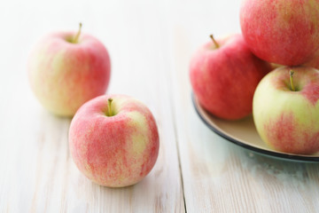 Freshly picked organic light pink apples. White wooden table, high resolution.