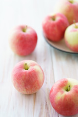 Freshly picked organic light pink apples. White wooden table, high resolution.