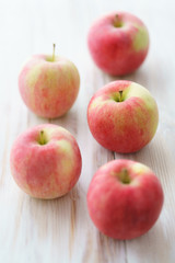 Freshly picked organic light pink apples. White wooden table, high resolution.