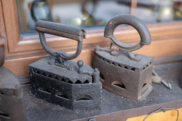 Old irons for ironing linen. Home accessories from the last century set on the windowsill.