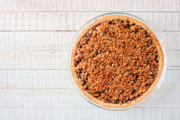 Apple crumble pie, above view on a white wood background. Homemade autumn dessert.