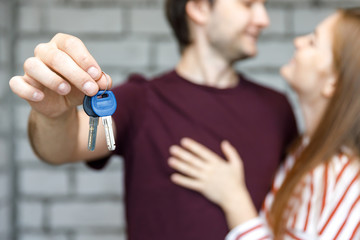 Young smiling couple showing keys to new home